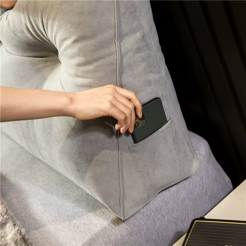 Hand placing a phone into the side pocket of a gray wedge pillow