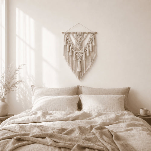 Cream macrame wall hanging above a bed in a neutral bedroom