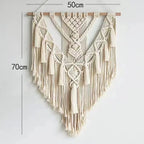 Macrame wall hanging displayed on a white wall with potted plants underneath showing scale and styling