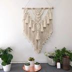 Cream macrame wall hanging on a blue wall with warm lamp light showing evening ambiance
